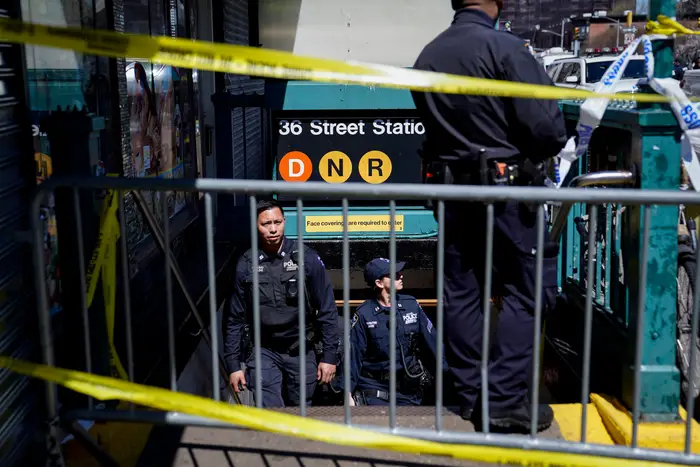 Police personnel stand in the subway entrance to the 36th Street station, which is barricaded